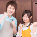 ガッツポーズするエプロン姿の男女カップル